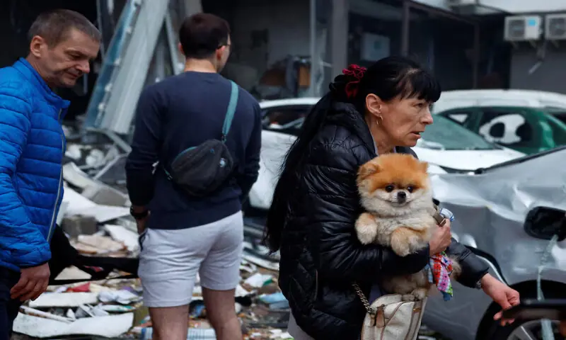 A woman carries a dog at the site of an apartment building which was heavily damaged during Russian missile and drone strikes in Kyiv, Ukraine, on Monday. -- Reuters
