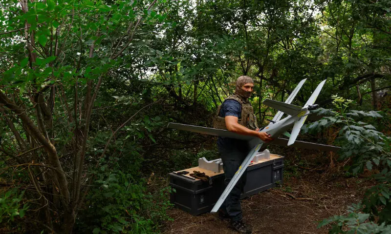 A service member of the Ukrainian Armed Forces carries a RAM-2X strike drone to a launch point while he works at a position near a front line in southern Ukraine. -- Reuters