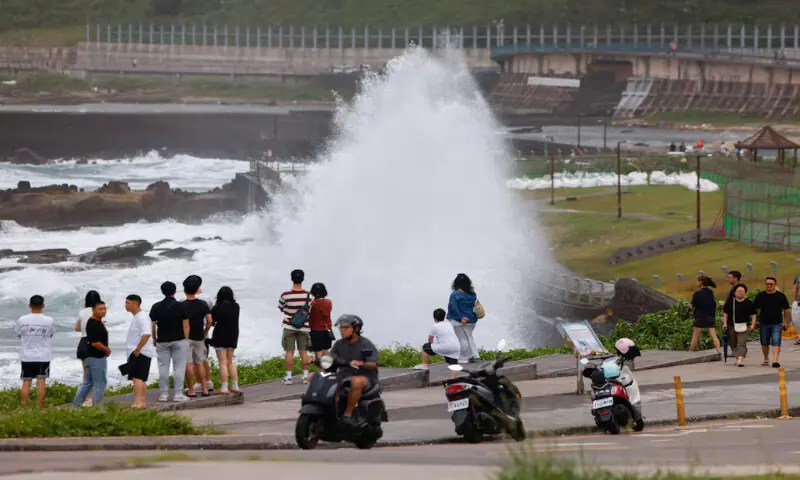 People watch waves crashing against the shoreline as Typhoon Bavi approaches in Keelung, Taiwan. -- Reuters