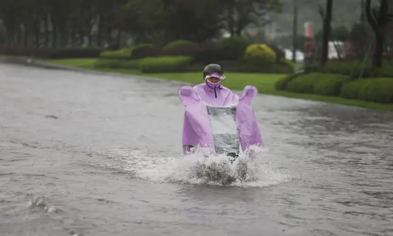 A person rides an electric scooter through a flooded road after heavy rain brought by Typhoon Bavi in Wenzhou, Zhejiang province, China, on Sunday. -- Reuters