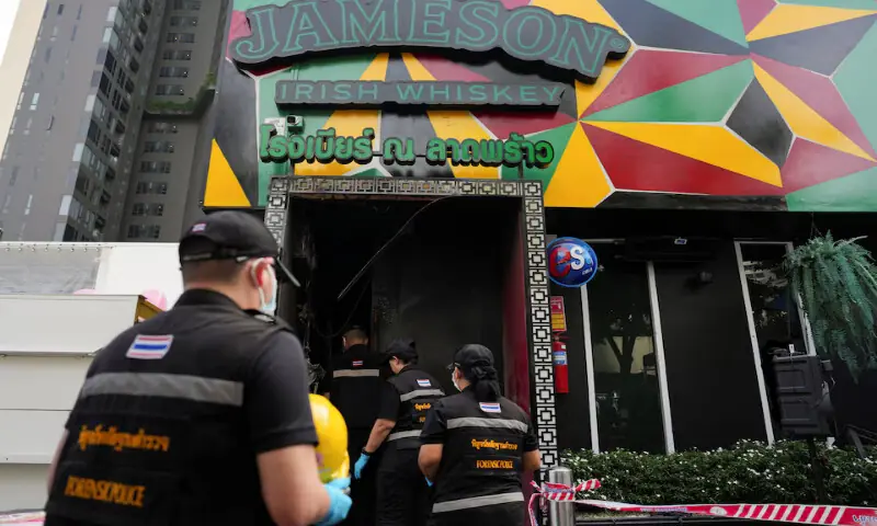 Forensic police officials arrive to inspect the site of a deadly fire at a pub in Bangkok, Thailand, on Monday. -- Reuters