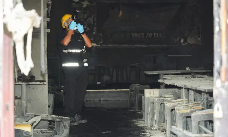 A forensic police official takes photographs the site of a deadly fire at a pub in Bangkok, Thailand, on Monday. -- Reuters