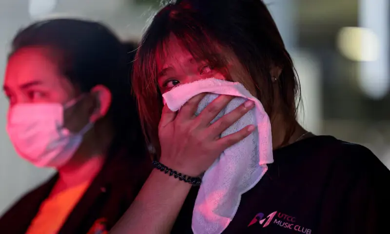 A woman, whose older sister died in a fire at a pub in Bangkok, reacts near the scene on Monday. -- Reuters