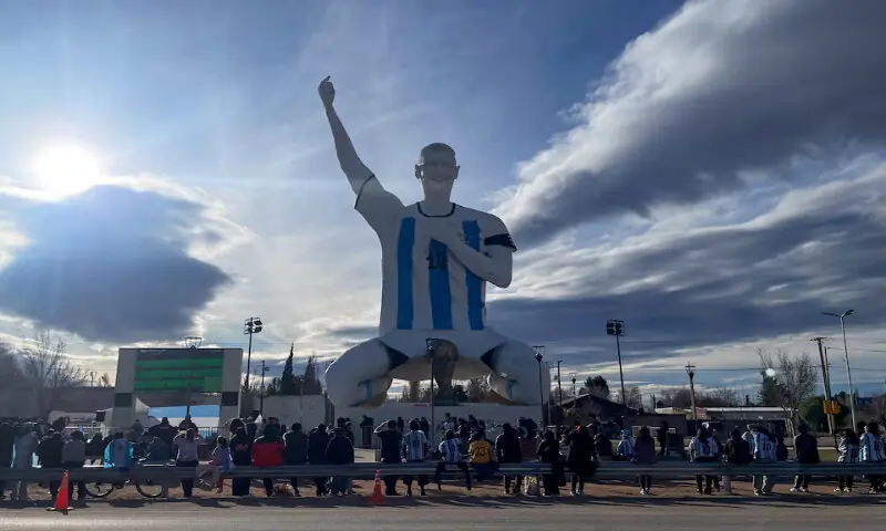 People gather by a statue of Lionel Messi while watching the World Cup semi-final between Argentina and England in Cutral Co, in the Patagonian province of Neuquen, Argentina. -- Reuters
