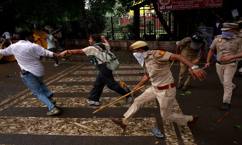 A security force official wields his baton against protesters in New Delhi. -- Reuters A security force official wields his baton against protesters in New Delhi. -- Reuters