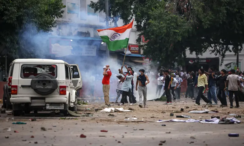 Masked protesters hold an Indian flag near plumes of tear gas in New Delhi. -- Reuters Masked protesters hold an Indian flag near plumes of tear gas in New Delhi. -- Reuters