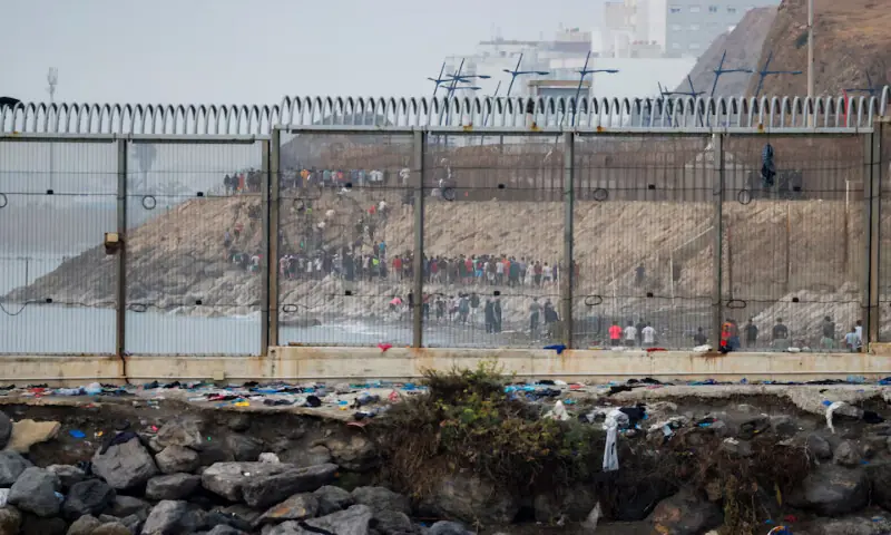 Migrants walk on the Moroccan side of the border as seen from Cueta, Spain, on Saturday. -- Reuters