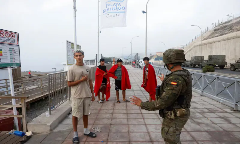 A Spanish soldier gestures to migrants on their way to the border to Morocco in Ceuta, Spain. -- Reuters
