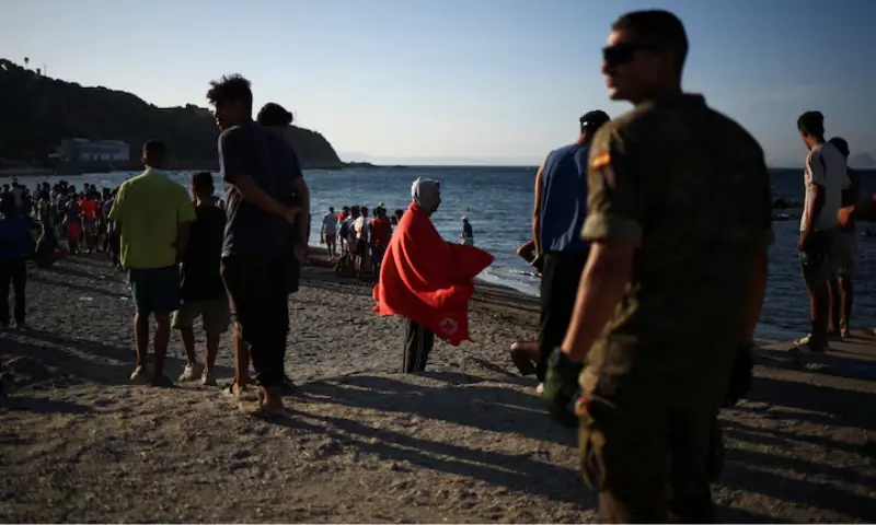 Migrants stand on a beach in Ceuta, following mass crossings of migrants on foot and by sea from Morocco into Spanish territory, in Ceuta, Spain. -- Reuters