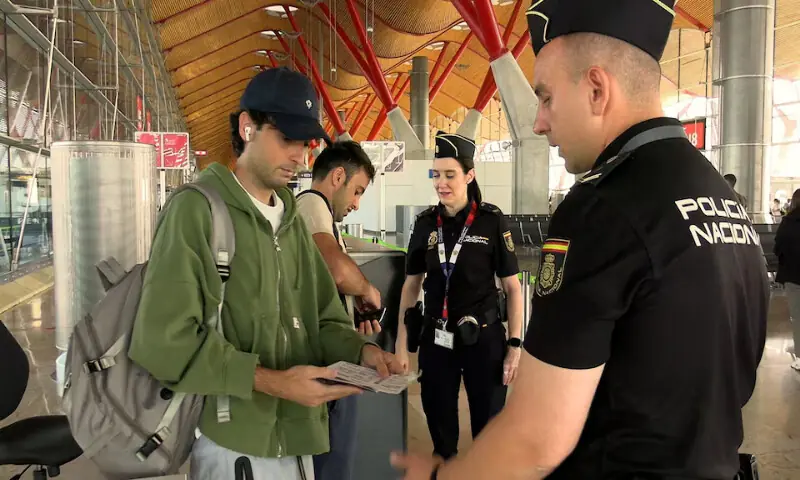 Spanish national police officers check the documents of travellers arriving from Italy at Madrid-Barajas Airport in Madrid. -- Reuters