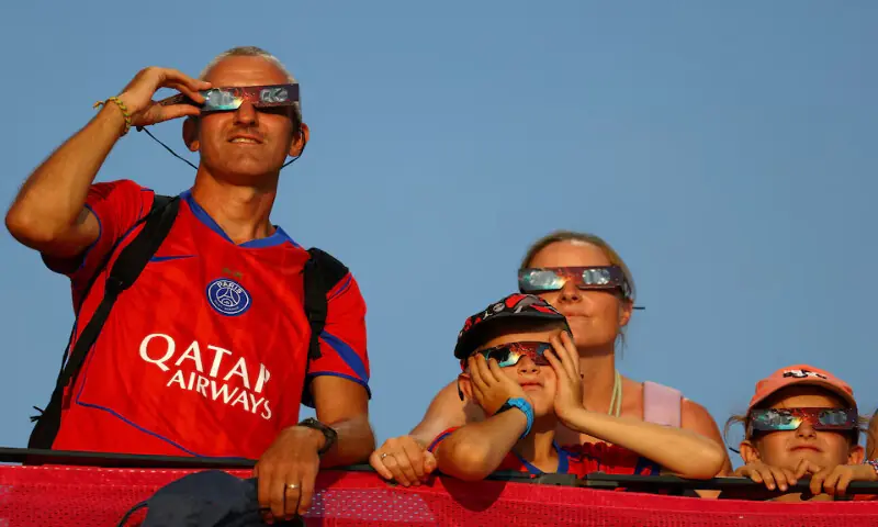 Spectators in the stands watch the solar eclipse through protective glasses. -- Reuters