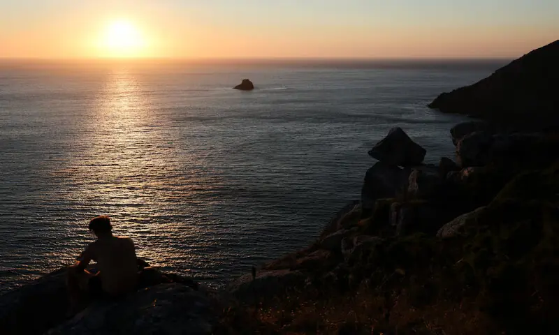 A tourist looks at the sunset the day before the solar eclipse, on the Costa da Morte ("Coast of Death"), once considered the end of the world and a traditional destination for pilgrims completing the Camino de Santiago, in northwestern Spain. -- Reuters