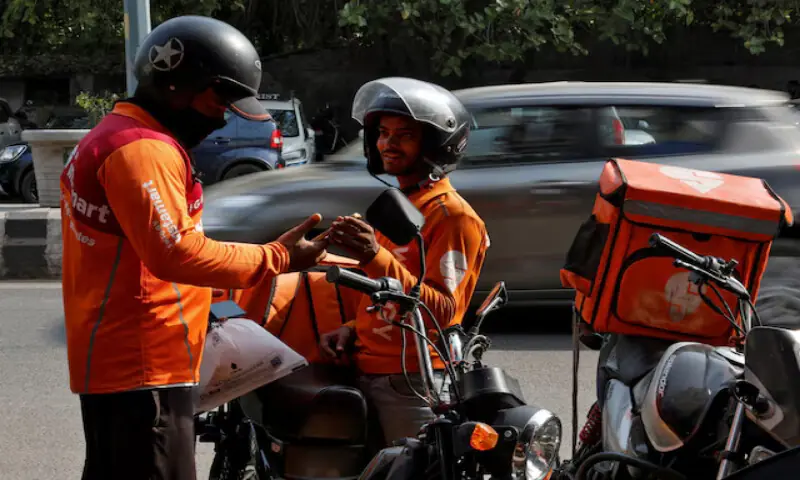 Gig workers prepare to deliver orders outside Swiggy's grocery warehouse at a market area in New Delhi, India. -- Reuters file