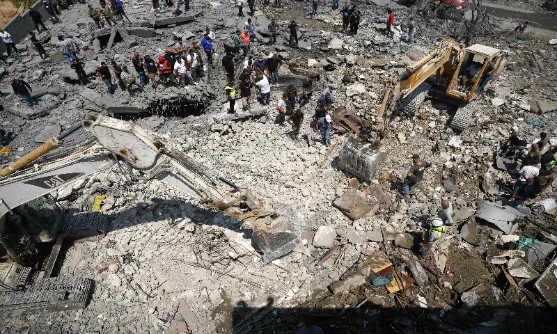 Heavy machinery, first aid responders and residents search the site of an Israeli airstrike that targeted a neighbourhood in the southern Lebanese village of Deir al-Zahrani on August 15, 2026. AFP