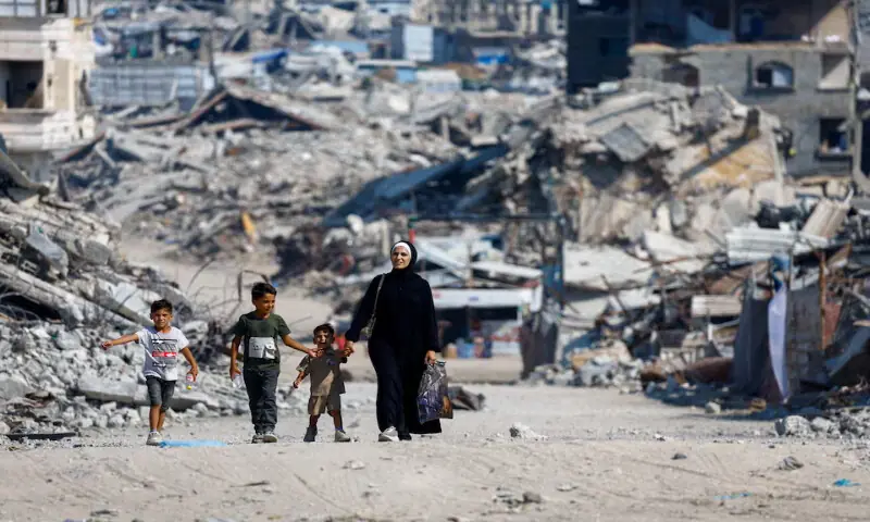 Palestinians walk past the rubble of residential buildings destroyed in Israeli strikes in Gaza City. -- Reuters
