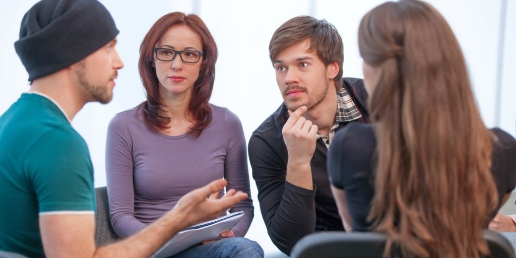 Group of people listening to what young man saying. Close up of several people in workshop